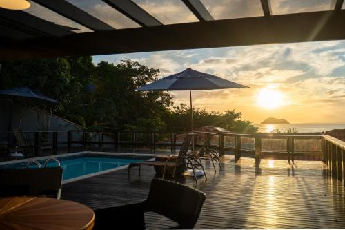 a patio with a pool and tables and an umbrella at Buzios Mar Hotel in Búzios