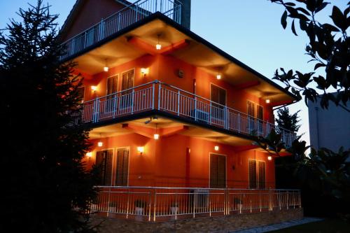 an orange building with a balcony and lights on it at Demaj House in Grilë