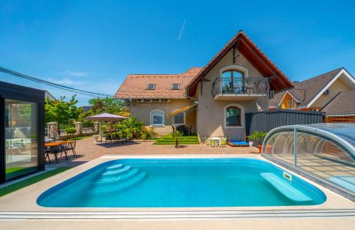 a house with a swimming pool in front of a house at Helka Apartmanház in Balatonlelle