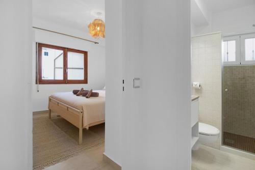 a white bedroom with a bed and a bathroom at RBL Paraíso Moraira Beachfront apartment in Moraira