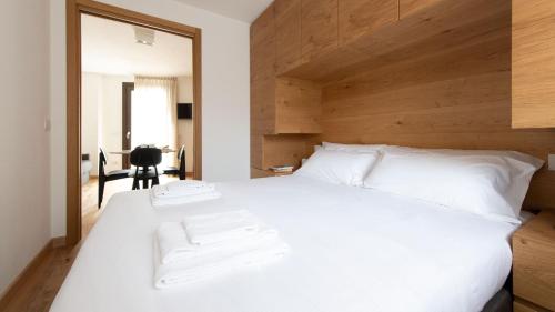 a bedroom with a white bed with a wooden headboard at Italianway - Al Forte 6 in Valdisotto