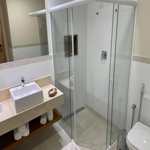 a bathroom with a glass shower and a sink at Hotel Chateau in Campos do Jordão