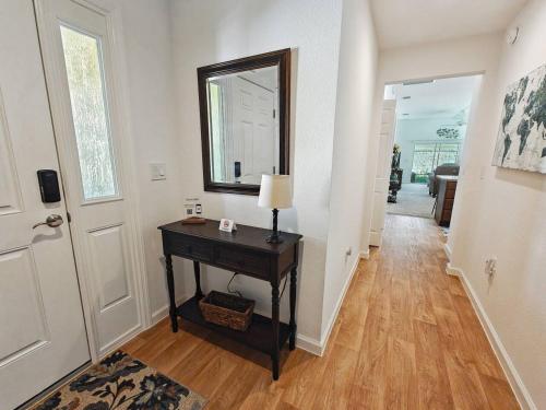 a hallway with a table with a lamp and a mirror at Charming Courtyard Villa In The Villages in Wildwood