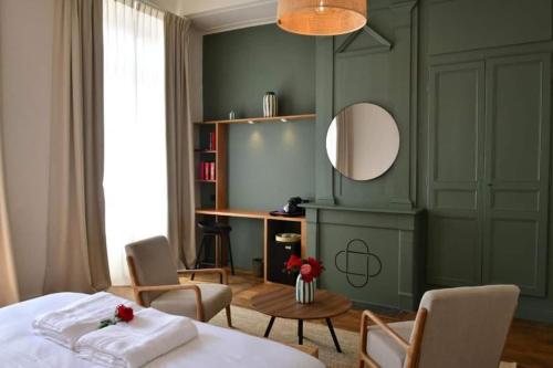- une chambre avec un lit, des chaises et un miroir dans l'établissement Les Chambres du Cloître, la Confiseuse, à Limoges