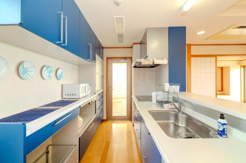 eine Küche mit blauen und weißen Schränken und einem Waschbecken in der Unterkunft max 8 people, 2LDK -Sion-Maezato in Ishigaki-jima
