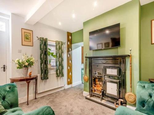 a living room with a fireplace and green walls at Hutton Mount Retreats in Ripon
