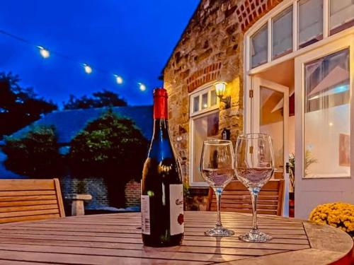 a bottle of wine sitting on a table with two wine glasses at Hutton Mount Retreats in Ripon