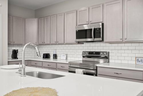 a white kitchen with a sink and a microwave at Spacious Whitestown Getaway in Whitestown