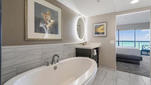 a bathroom with a tub and a bedroom with a bed at Luxury Oceanfront High Floor at Waikiki Beach Tower in Honolulu