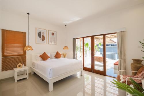 une chambre blanche avec un lit et un balcon dans l'établissement Villa OG Cruz and OG Cove - Central & Modern Canggu Pool Villas - Sleeps 14, à Canggu