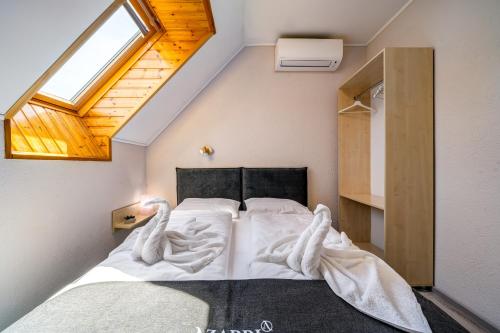 a bedroom with a bed with white sheets and a window at Helka Apartmanház in Balatonlelle