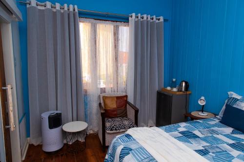a bedroom with a bed and a chair next to a window at Wildhorses B&B and Self Catering in Lüderitz