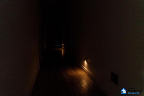 an empty room with a dark room with a light on the wall at Luxury Desert Paradise in Kalgoorlie