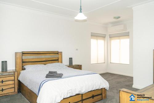 a bedroom with a large bed and two windows at Luxury Desert Paradise in Kalgoorlie