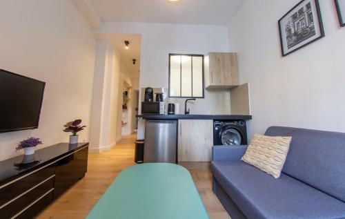 un salon avec un canapé bleu et une cuisine dans l'établissement Agréable appartement dans le 13ème arrondissement, à Paris