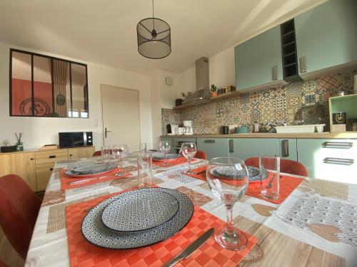 une table avec des verres et des assiettes au-dessus dans l'établissement La Valériane - Clim, balcon et garage privé, à Montélimar