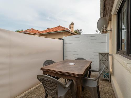 a wooden table and chairs on a patio with a fence at Appartement pour 3 à Mimizan Plage, à 50m de l'océan avec terrasse et parking, ménage inclus - FR-1-50-123 in Mimizan