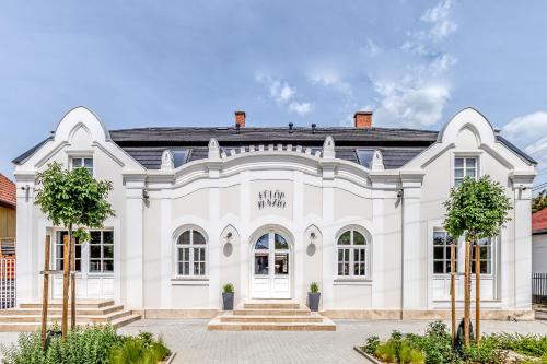 a large white building with trees in front of it at Fulop Panzio Rooms in Révfülöp