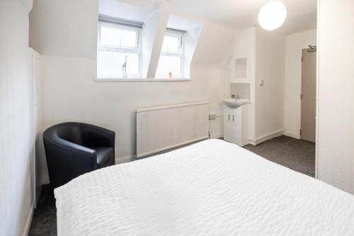 a bedroom with a white bed and a black chair at OYO A Better Night Hotel - Manchester Salford in Manchester