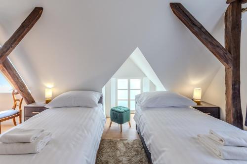 two beds in a attic room with a window at Fulop Panzio Rooms in Révfülöp