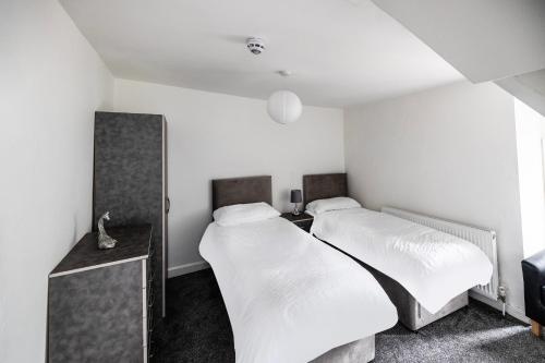 two beds in a small room with white sheets at OYO A Better Night Hotel - Manchester Salford in Manchester