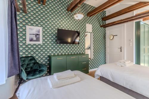 a bedroom with two beds and a tv on the wall at Fulop Panzio Rooms in Révfülöp
