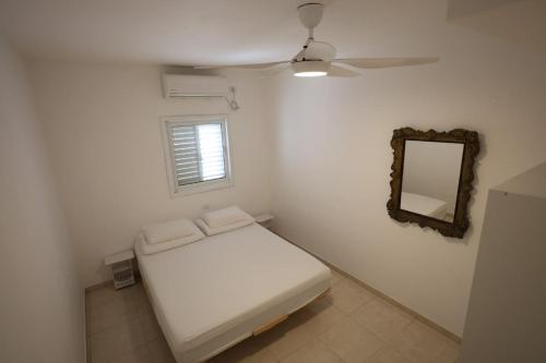 a small white room with a bed and a mirror at Vacation rental in Netanya