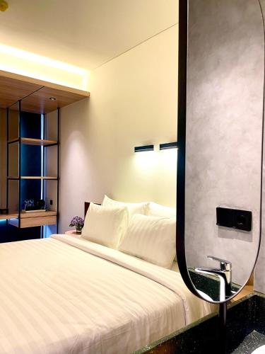 a bedroom with a large bed with a mirror at ATOOI Hotel Alam Sutera in Serpong