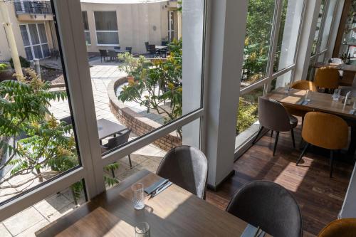 an empty restaurant with tables and chairs and windows at CE Plaza Hotel in Siófok