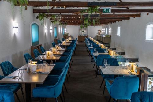 a row of tables in a restaurant with blue chairs at CE Plaza Hotel in Siófok