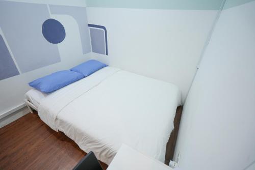 a bedroom with a white bed with blue pillows at Aimelia guest house in Petaling Jaya
