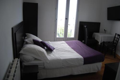 a bedroom with a bed with purple and white pillows at Hôtel Azur in Nice