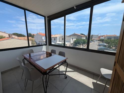 une table et des chaises dans une pièce avec des fenêtres dans l'établissement Appartement T2 rénové, climatisé, proche plage avec parking à Port-la-Nouvelle - FR-1-797-59, à Port-la-Nouvelle