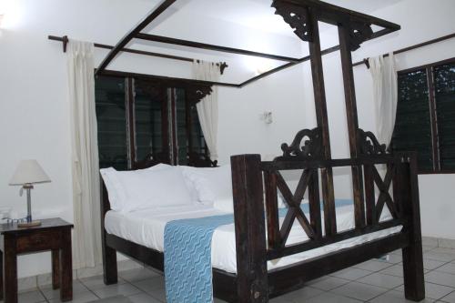 a bedroom with a canopy bed with white sheets at Blessing Holiday Homes - Diani Beach in Diani Beach