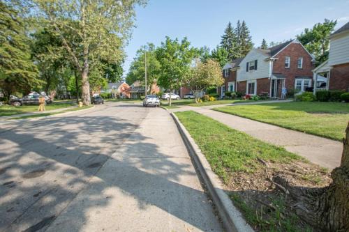 a street in a residential neighborhood with a car driving down the street at Newly Renovated Townhouse on a Tranquil Street in Dearborn