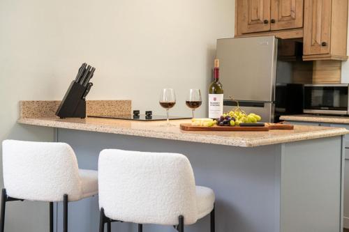 a kitchen with two white chairs and a counter with wine glasses at King Bed-Step to Madeira Beach-Heated Pool-Private in St Pete Beach