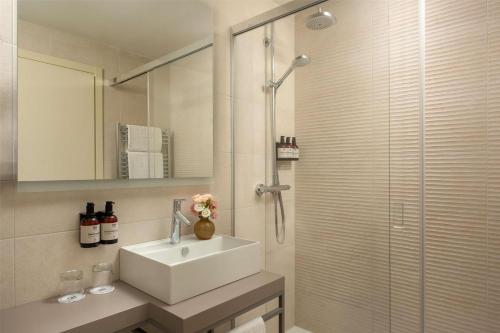a bathroom with a sink and a glass shower at NH Trieste in Trieste