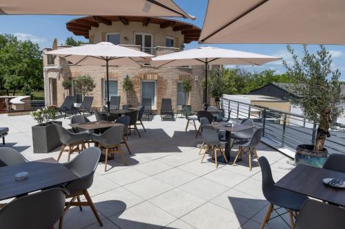 a patio with tables and chairs and umbrellas at CE Plaza Hotel in Siófok