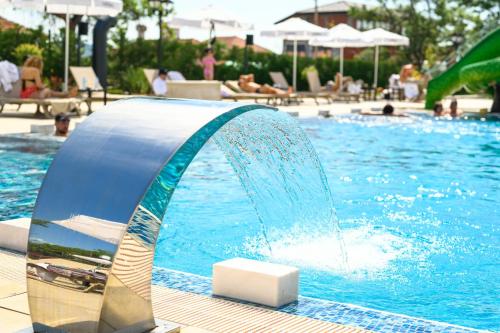 a pool with a water fountain in a swimming pool at Empire Balneo & Spa Hotel in Hisarya