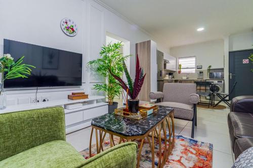 a living room with a couch and a table with a tv at Luxurious sandton apartment with Inverter in Sandton