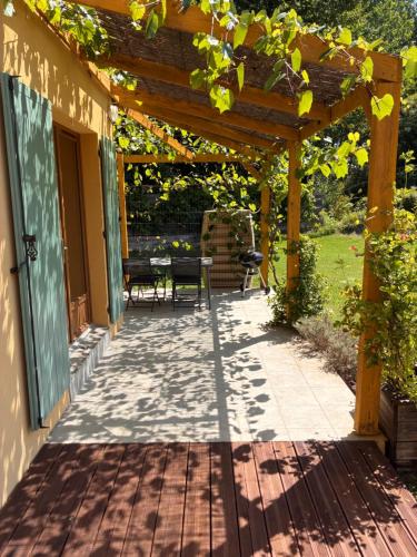 une terrasse avec une pergola en bois et une table dans l'établissement Au doux paillis Sorgue, au Thor