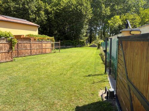 une arrière-cour avec une clôture et une cour d'herbe dans l'établissement Au doux paillis Sorgue, au Thor