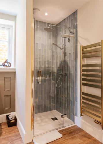 a bathroom with a shower with a glass door at Cliff Farmhouse B&B Suites in Hunstanton