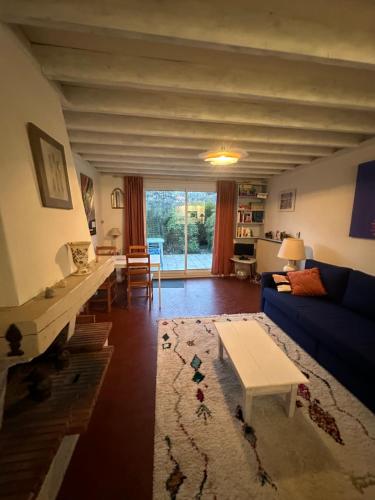 un salon avec un canapé bleu et une table dans l'établissement Cottage with Garden 5mn Beach, à Cabourg