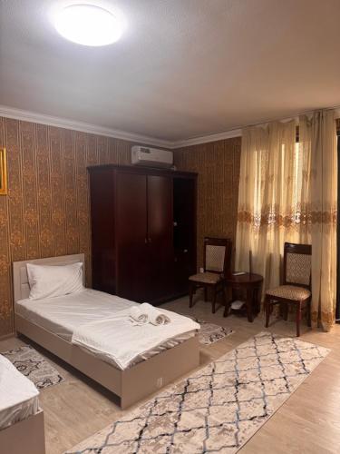 a bedroom with a bed and two chairs in it at Avlod Guest House in Samarkand