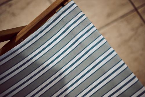 a wooden chair with blue and white stripes on it at La Ferme de Jeanne in Francescas