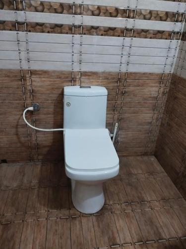 a white toilet in a bathroom with a wooden floor at Beach Front Home Stay in Irimbranallūr