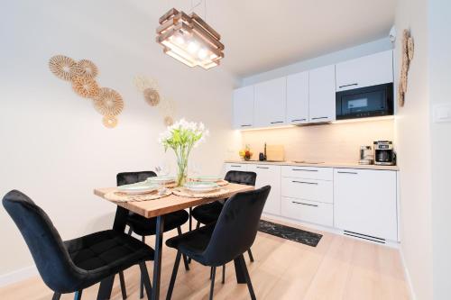 a kitchen with a wooden table and black chairs at Laguna Beskidów Resort - Apartament Orzechowy in Zarzecze