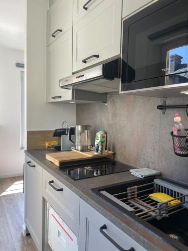 une cuisine avec des armoires blanches et un four à plaques de cuisson dans l'établissement Le nid de la cathédrale, à Bayeux