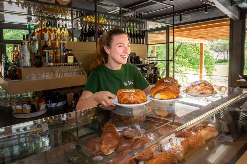 a woman is standing behind a bakery counter with pastries at hu Firenze Certosa camping in town in Impruneta